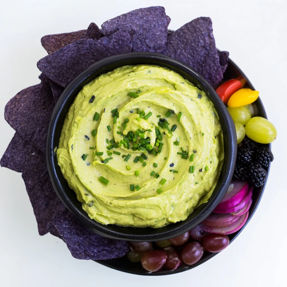 This Witch's Brew Cauldron appetizer showcases an avocado dip with smoky red onion and purple grapes.