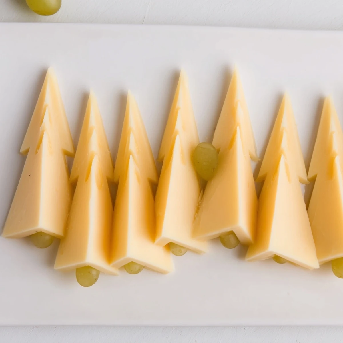 A festive The Tannenbaum Border cheese board with green grapes, perfect for holiday entertaining.