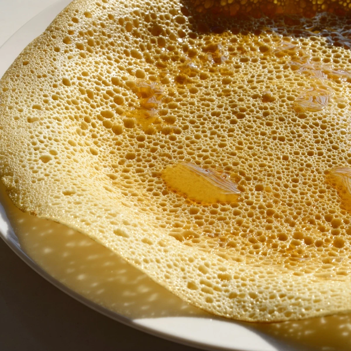 Golden-brown Moroccan Baghrir crepes, with a bubbly surface, ready to be soaked in honey-butter.