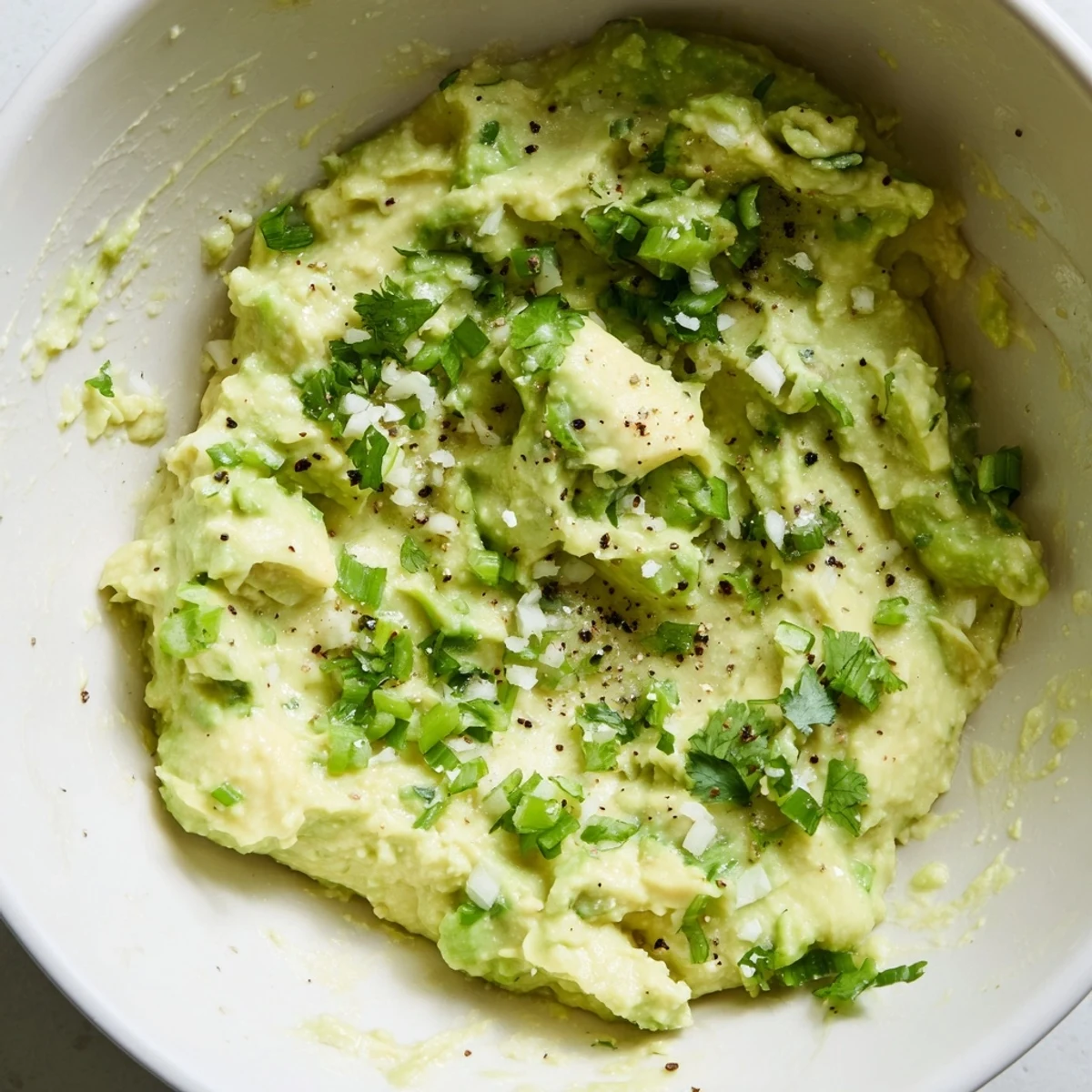 Creamy avocado lime dip with fresh cilantro and lime wedges, served with crisp tortilla chips for dipping.  