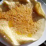 Warm and airy, these homemade Moroccan Baghrir crepes are plated and drizzled with sweet, glossy honey.