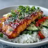 Vibrant toppings like toasted sesame seeds, sliced scallions, and lime wedges garnish this healthy Asian-Inspired Salmon Bowl.  
