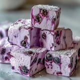 Fluffy Black Currant Marshmallows with a vibrant lavender hue melting into a steaming mug of hot cocoa.