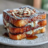 Rich and creamy almond croissant French toast featuring brioche bread, luscious almond filling, and a crunchy almond topping for breakfast bliss.