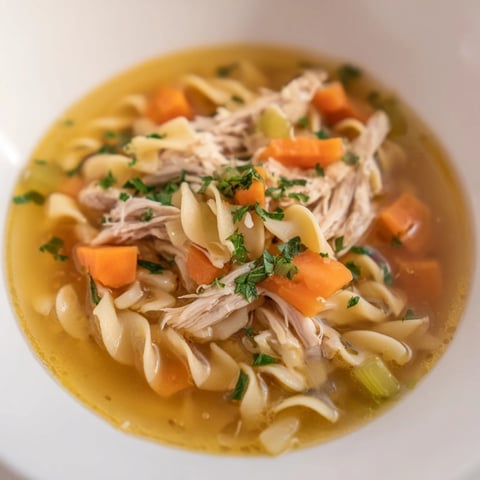 Steaming bowl of Classic Chicken Noodle Soup with vibrant veggies and tender chicken.