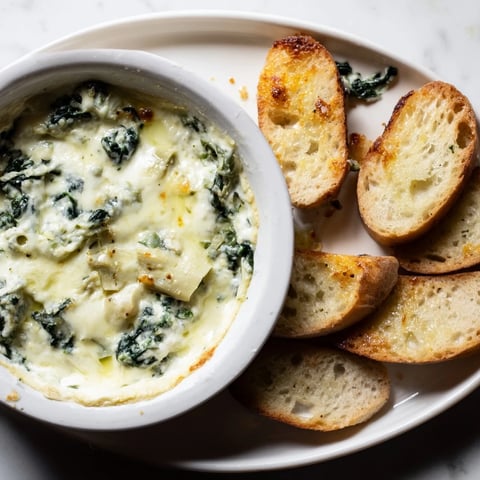 Creamy Spinach Artichoke Dip, bubbling hot and served with crispy, golden baguette slices.