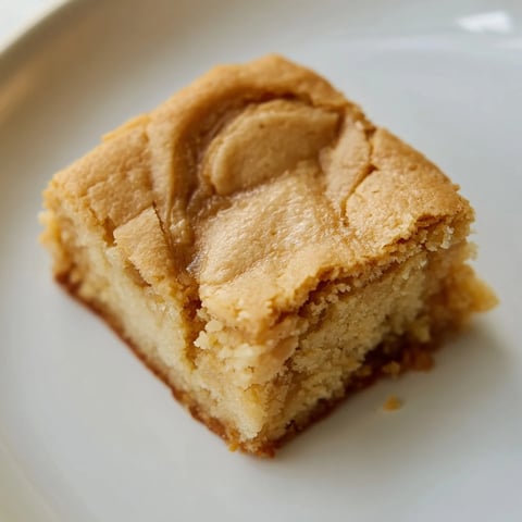 Warm, golden-brown Peanut Butter Mochi Cake, a chewy dessert perfect with a dollop of whipped cream.