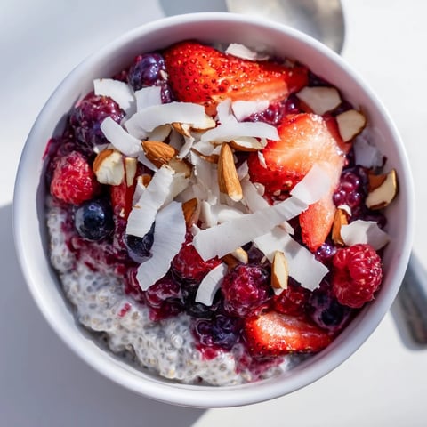 Creamy berry chia pudding layered in a clear glass, bursting with fresh, vibrant berries and flavor.