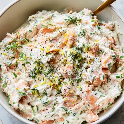 Creamy smoked salmon dip garnished with fresh dill and lemon wedges served with bagel chips.