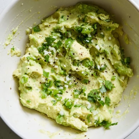 Creamy avocado lime dip with fresh cilantro and lime wedges, served with crisp tortilla chips for dipping.  