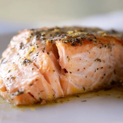 Flaky baked salmon rests atop a vibrant salad of quinoa, mixed greens, and fresh herbs, drizzled with zesty lemon vinaigrette.  