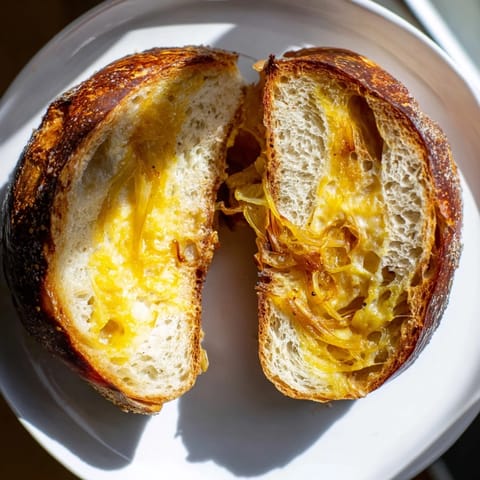 Close-up of a perfectly grilled Caramelized Onion and Gruyère Grilled Cheese, ready to be sliced and enjoyed.