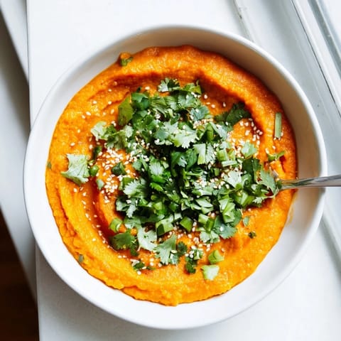 Roasted carrots blended with fresh ginger create a vibrant orange dip, perfect as a healthy vegetarian appetizer spread.