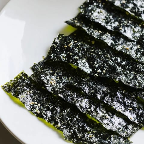 Golden-brown roasted seaweed chips glisten with sesame oil and fine sea salt, ready to snack.  