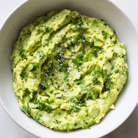 A vibrant bowl of homemade avocado lime dip, garnished with chopped cilantro, ready for a party snack.  