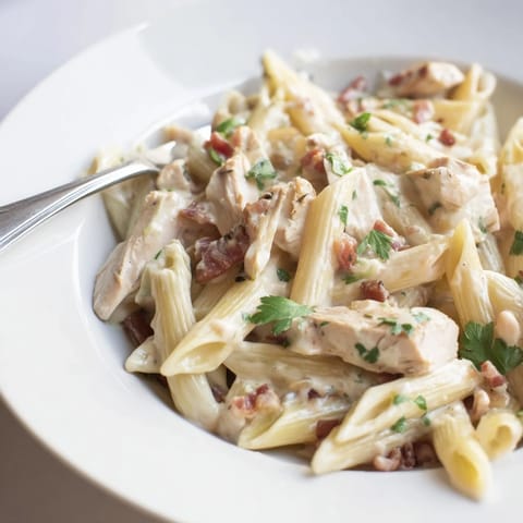 Savory Creamy Chicken Bacon Penne served in a white bowl, steam rising from creamy pasta with tender chicken pieces and smoky bacon.