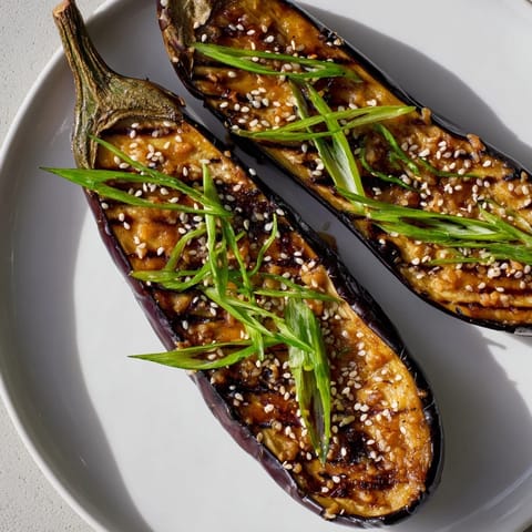 Miso glazed eggplant with tender roasted halves, vibrant green onions, and rich umami aroma for dinner.  