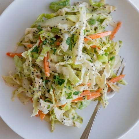 Green Cabbage and Apple Slaw served in a rustic bowl, featuring shredded carrots and a light, tangy apple cider dressing.