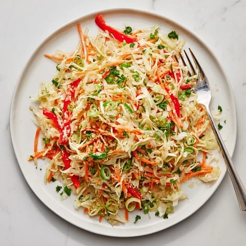 A vibrant bowl of Sauerkraut Slaw with shredded cabbage, grated carrots, and red bell peppers tossed in a light apple cider vinaigrette.