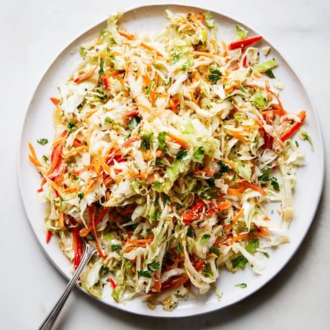 Freshly prepared Sauerkraut Slaw served in a rustic white bowl, garnished with green onions and parsley, highlighting its crunchy vegan texture.