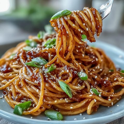 Spicy gochujang butter pasta with garlic, soy sauce, and honey, garnished with sesame seeds and spring onions.