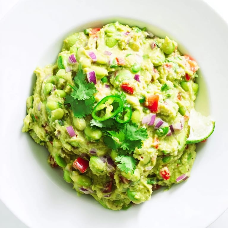 A bowl overflowing with smooth and green Edamame Guacamole, perfect for sharing at a gathering.