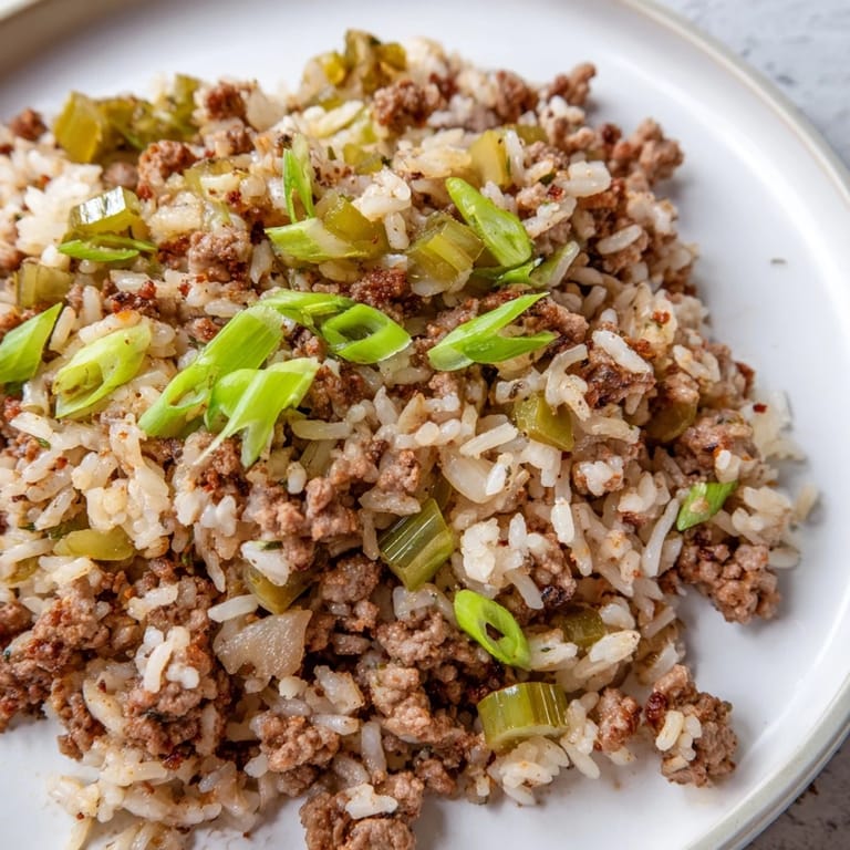 Hearty Cajun Dirty Rice, ready to serve, is shown garnished with fresh green onions for a tasty meal.