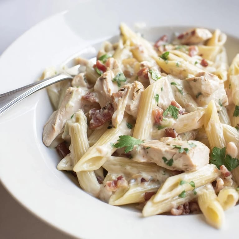 Savory Creamy Chicken Bacon Penne served in a white bowl, steam rising from creamy pasta with tender chicken pieces and smoky bacon.