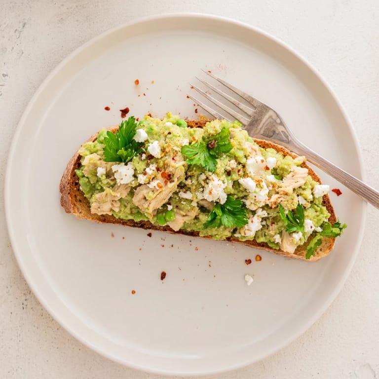 Golden toasted bread spread with vibrant green pea mash and tender shredded chicken, ready to be enjoyed warm for lunch.