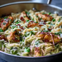 Creamy One-Pot Lemon Orzo with Chicken and Peas in a skillet with bright lemon zest and fresh parsley.